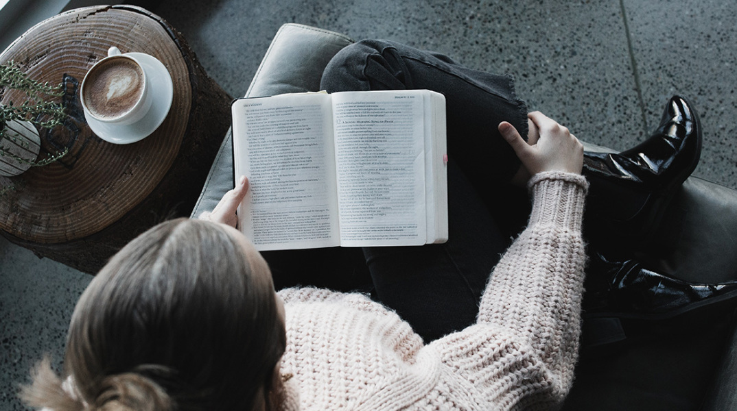 Κοπέλα κάθεται στον καναπέ και διαβάζει βιβλίο