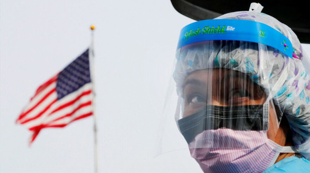 Υγειονομικός στις ΗΠΑ φορά μάσκα για κορωνοϊό με φόντο την αμερικανική σημαία