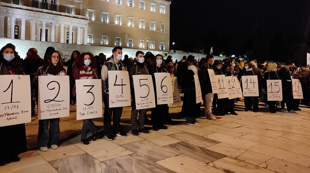 Συγκεντρωμένοι κρατούν πανό έξω από την Βουλή για τις γυναικοκτονίες 