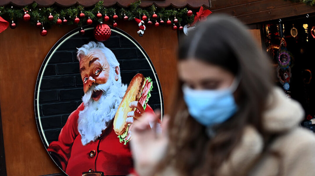 Κοπέλα με μάσκα για κορωνοϊό σε χριστουγεννιάτικη αγορά στο Λονδίνο