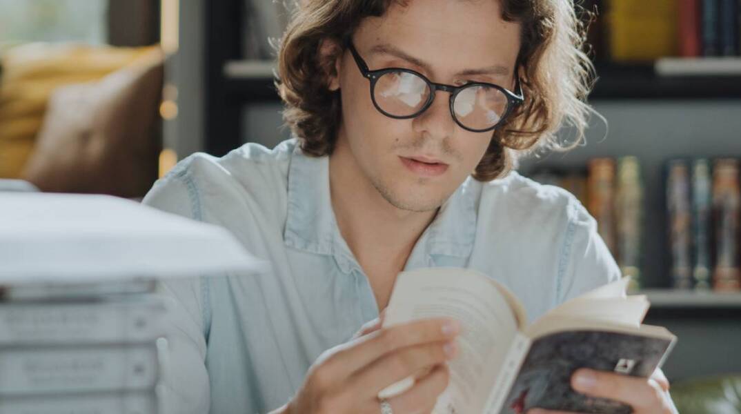 Νεαρός άντρας με γυαλιά, που διαβάζει βιβλίο