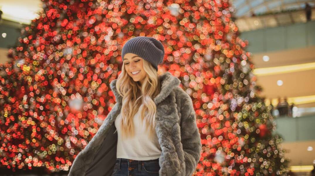 Ξανθιά κοπέλα μπροστά από το χριστουγεννιάτικο δέντρο