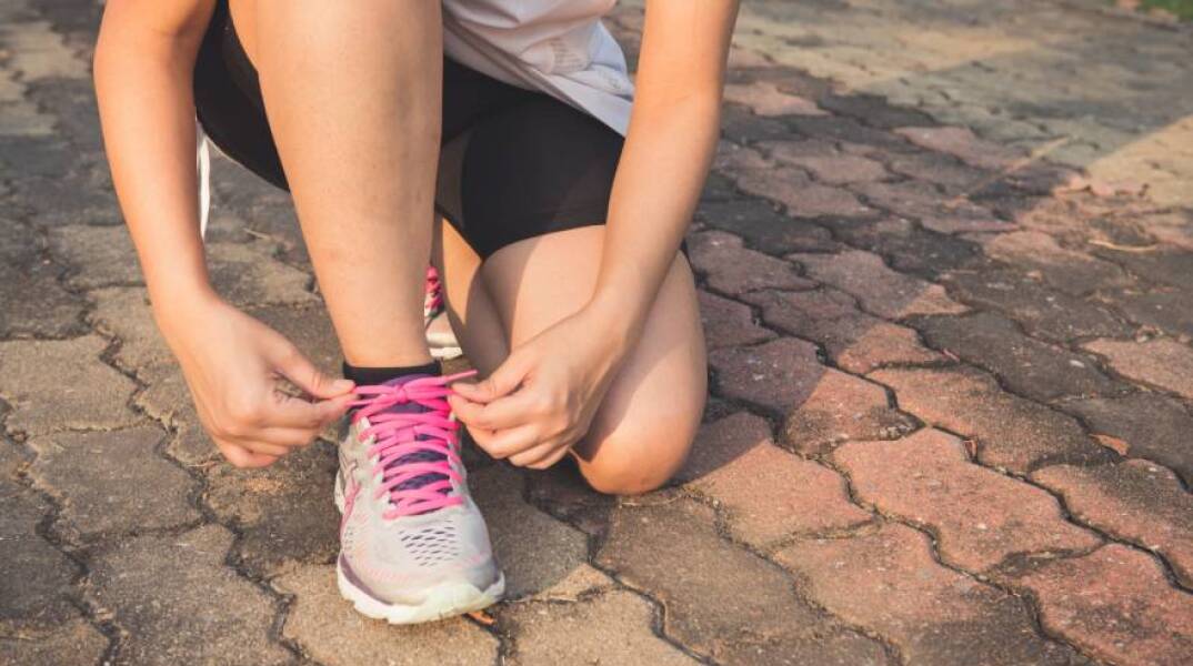 Μια γυναίκα δένει τα κορδόνια στα αθλητικά της παπούτσια