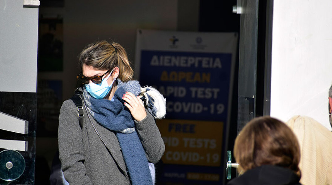 Γυναίκα με μάσκα για κορωνοϊό βγαίνει από κτίριο όπου διενεργείται rapid test από τον ΕΟΔΥ