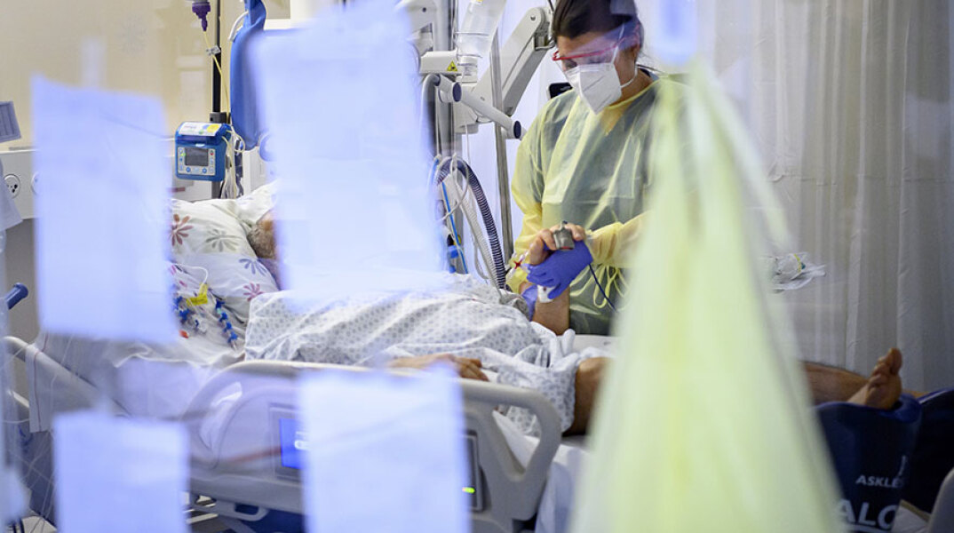 Νοσηλεύτρια φροντίζει ασθενή με κορωνοϊό σε ΜΕΘ νοσοκομείου στη Λωζάνη
