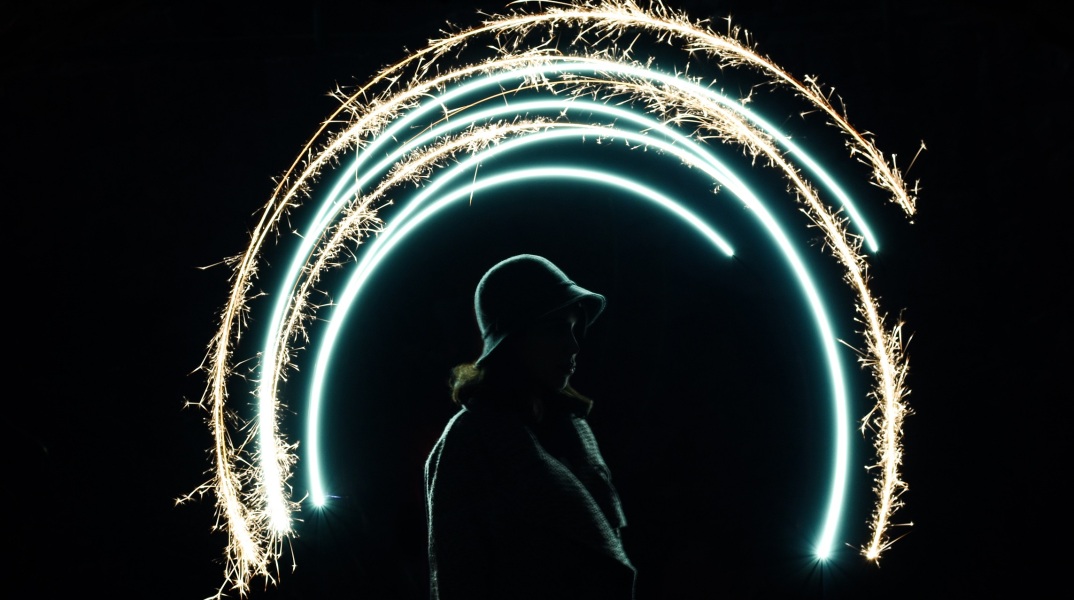 Γυναίκα με καπέλο που φωτίζεται από πυροτεχνήματα