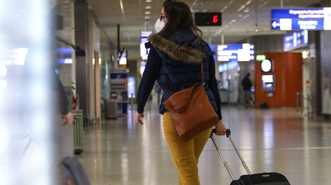 Γυναίκα ταξιδιώτης με μάσκα για τον κορωνοϊό στο αεροδρόμιο «Ελευθέριος Βενιζέλος»