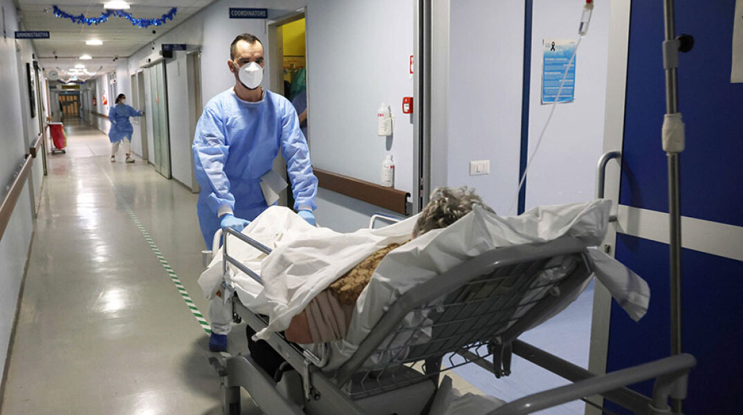 Υγειονομικός οδηγεί ασθενή με κορωνοϊό σε θάλαμο νοσοκομείου στην Κρεμόνα της Ιταλίας