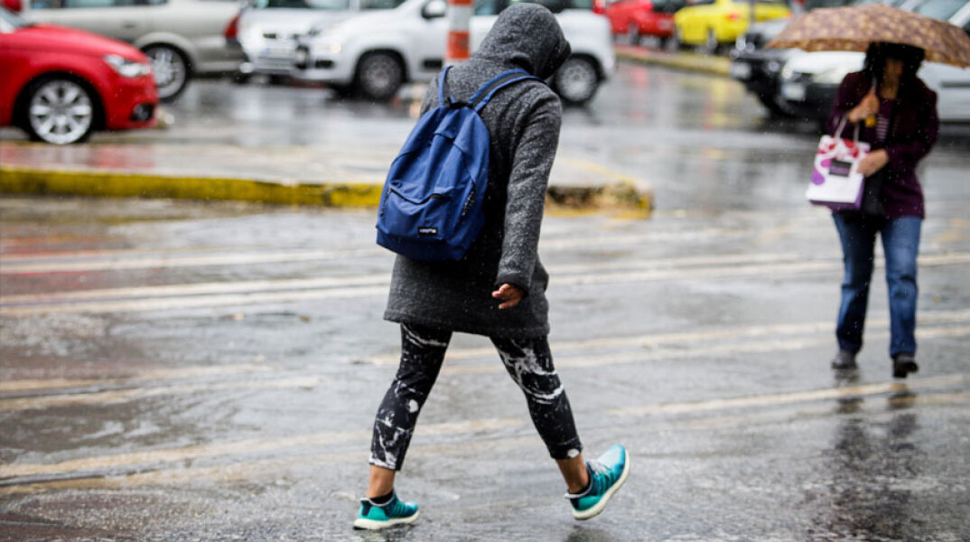 Άνθρωπος περπατά στη βροχή στο κέντρο της Αθήνας