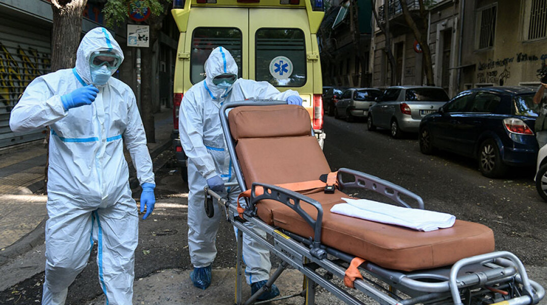Υγειονομικοί του ΕΚΑΒ για τη μεταφορά ασθενών με κορωνοϊό σπρώχνουν φορείο