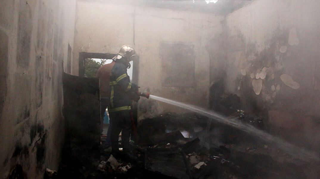 Πυροσβέστης σβήνει φωτιά σε κατοικία