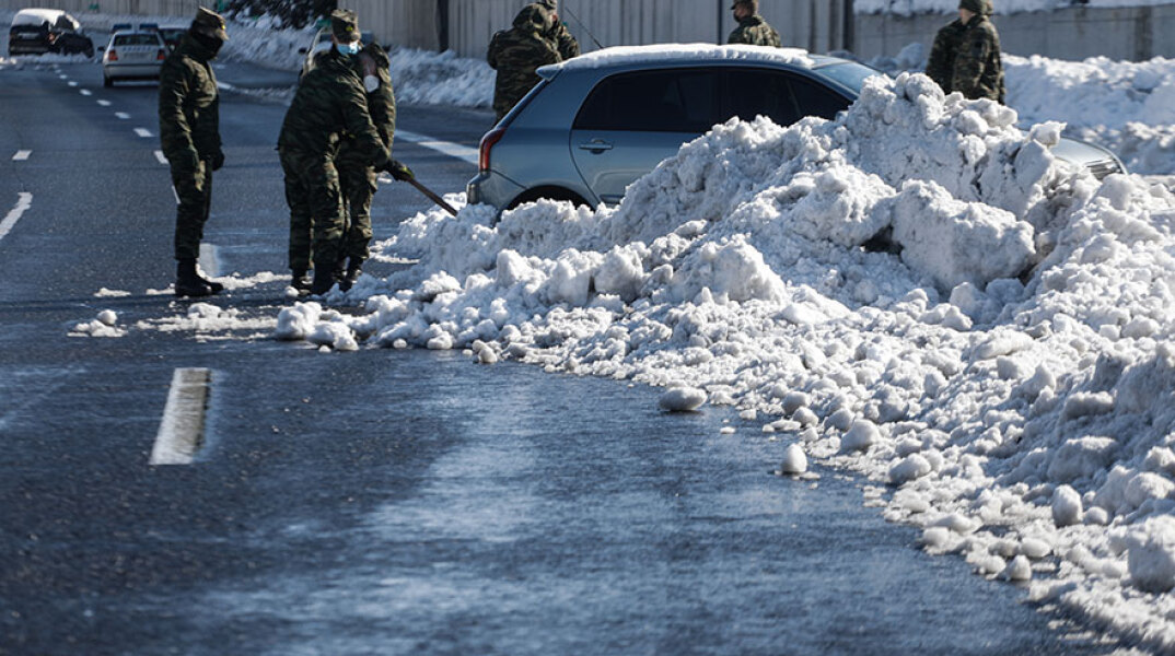 Στην Αττική Οδό στρατιώτες απομακρύνουν χιόνια από αυτοκίνητο