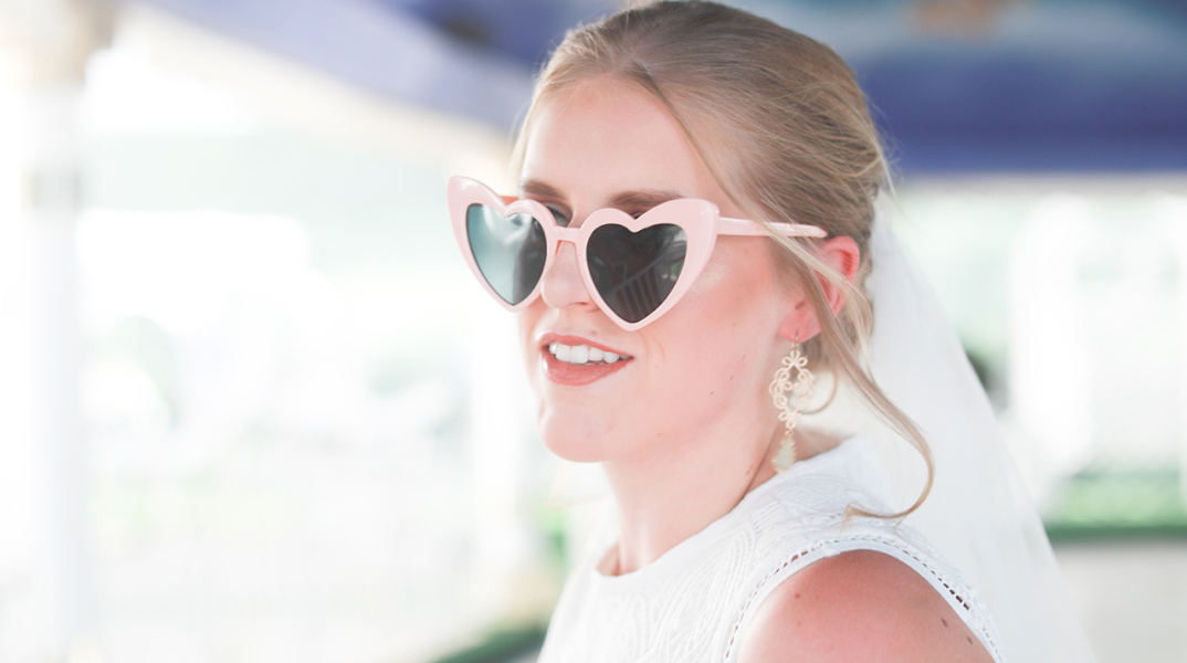 Ξανθιά κοπέλα ντυμένη νύφη με γυαλιά ηλίου σε σχήμα καρδιάς