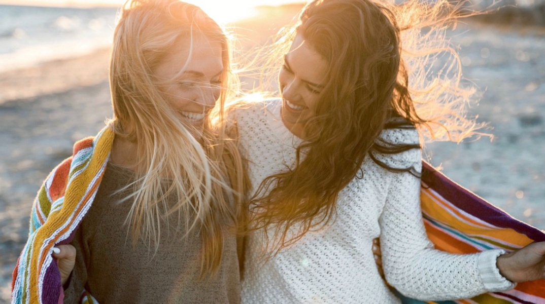 Δύο φίλες που γελούν στην παραλία.