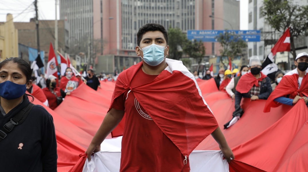 Διαδηλωτής στο Περού με κόκκινη μπλούζα και μάσκα προστασίας