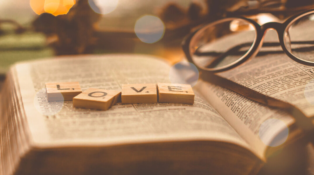 Ανοιχτό βιβλίο με ξύλινα γράμματα ακουμπισμένα που σχηματίζουν τη λέξη LOVE.