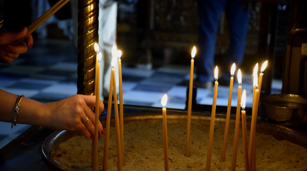 Πολίτες ανάβουν κερί σε εκκλησία
