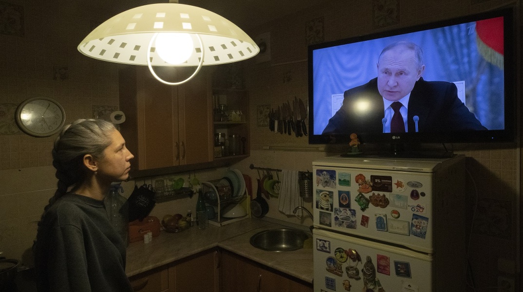 Γυναίκα παρακολουθεί στην τηλεόραση το διάγγελμα του Πούτιν για την εισβολή της Ρωσίας στην Ουκρανία