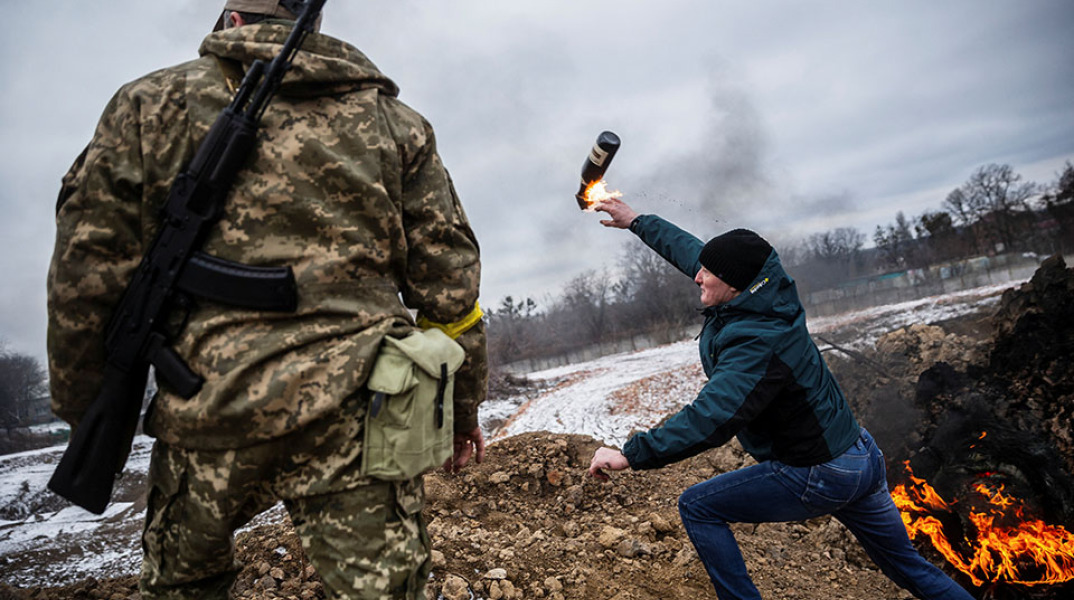 Πολίτης εκτοξεύσει μια βόμβα μολότοφ ενώ στο πλάι του στέκεται ένας Ουκρανός στρατιώτης. REUTERS/Viacheslav Ratynskyi