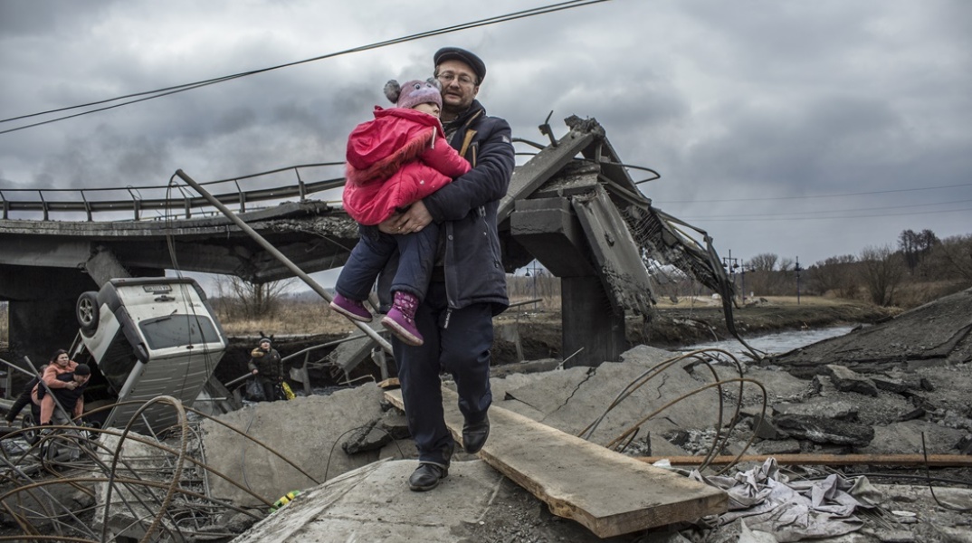 Πόλεμος στην Ουκρανία: Πατέρας κρατά το μωρό του στην αγκαλιά πάνω σε χαλάσματα της πόλης Ιρβίν