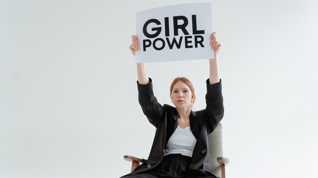 Γυναίκα σε καρέκλα που κρατά πινακίδα με τη φράση "Girl Power"