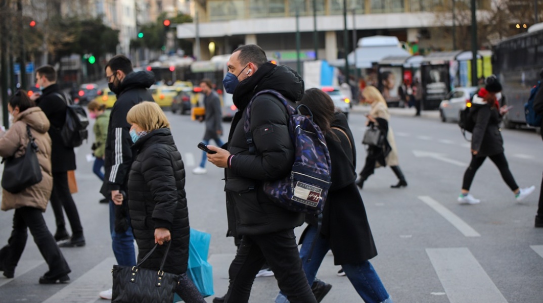 Πολίτες που φορούν μάσκα περπατούν στο κέντρο της Αθήνας