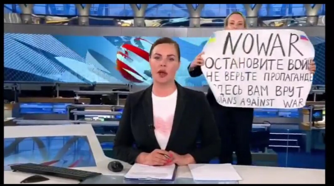 Διαδηλώτρια με πλακάτ κατά του πολέμου στην Ουκρανία πίσω από την παρουσιάστρια του δελτίου ειδήσεων της δημόσιας τηλεόρασης της Ρωσίας