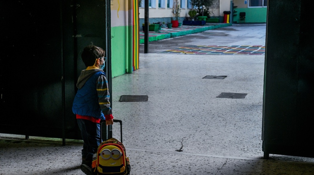 Μικρός μαθητής με την τσάντα του περιμένει να μπει στην τάξη του