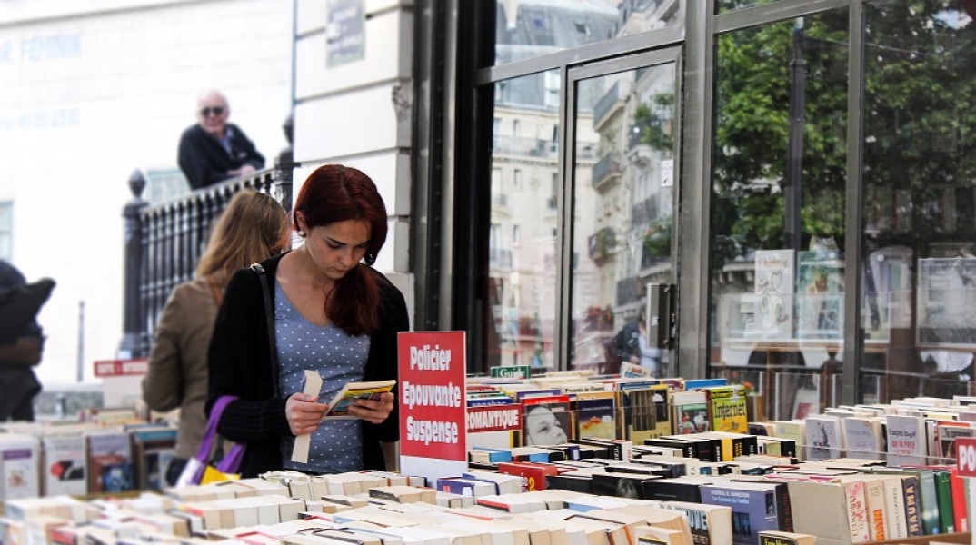 Γυναίκα διαβάζει βιβλίο σε βιβλιοπωλείο στη Γαλλία