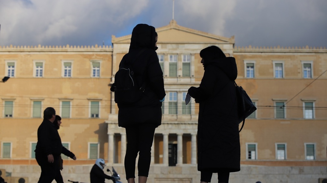 Πολίτες συζητούν με φόντο τη Βουλή των Ελλήνων