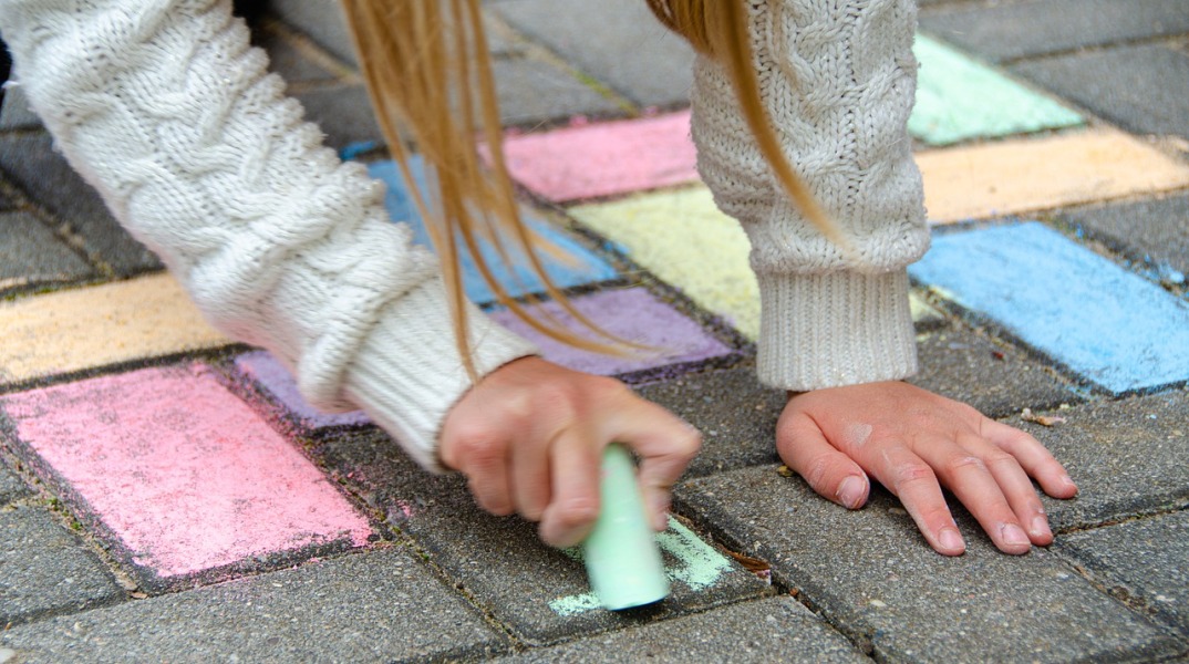 Κοριτσάκι ζωγραφίζει με κιμωλίες στο οδόστρωμα