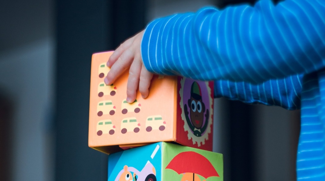 Χέρια παιδιού σε παιχνίδι με κύβους