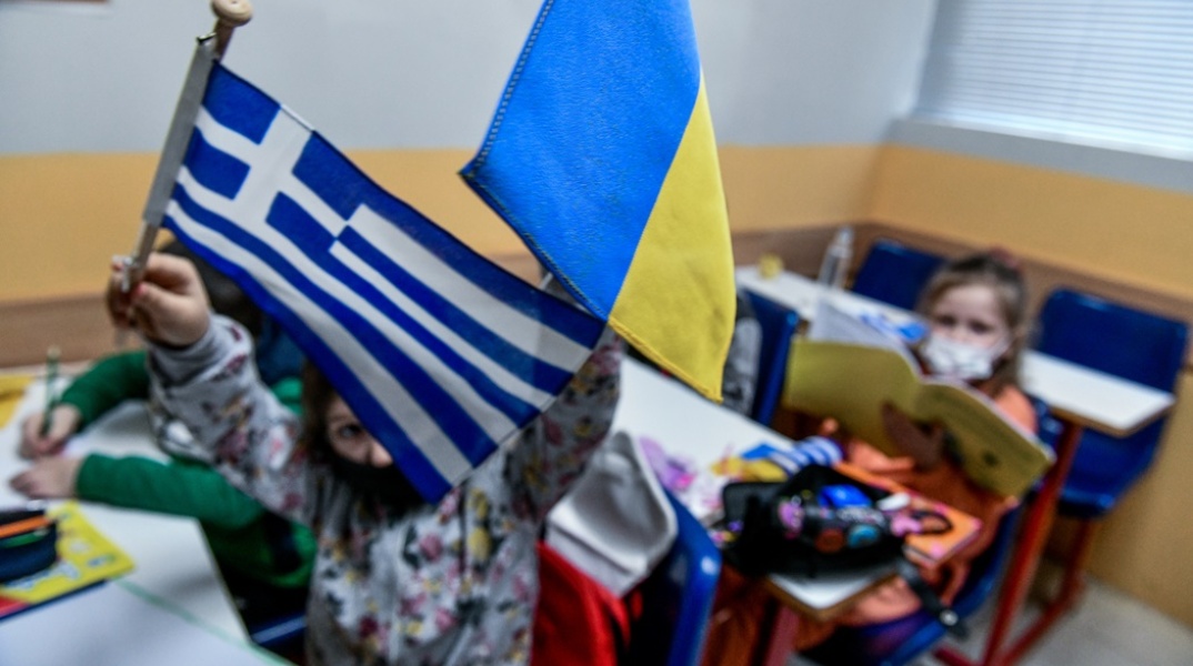 Παιδιά- πρόσφυγες από την Ουκρανία κρατούν την ελληνική και την ουκρανική σημαία σε χώρο όπου μαθαίνουν ελληνικά στο κέντρο της Αθήνας