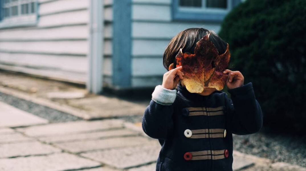 Μικρό παιδί που έχει βάλει ένα φύλλο μπροστά στο πρόσωπό του