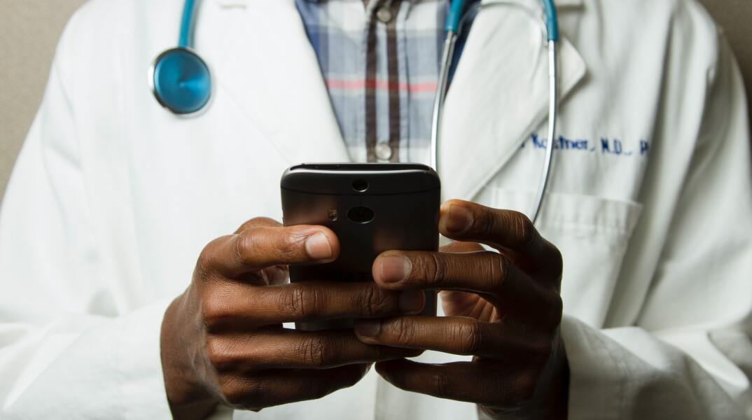 Γιατρός κρατά το κινητό του τηλέφωνο στα χέρια