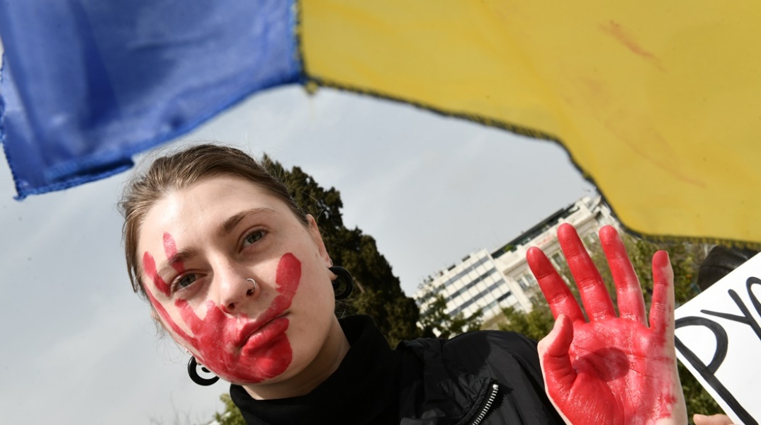 Γυναίκα με κόκκινο στα χέρια και το πρόσωπο συμβολίζει το αίμα που έχει χυθεί στην Ουκρανία
