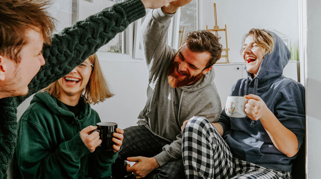 Άντρες και γυναίκες καθισμένοι πίνουν καφέ και γελούν