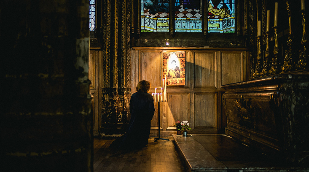 Γυναίκα προσεύχεται μέσα στην εκκλησία