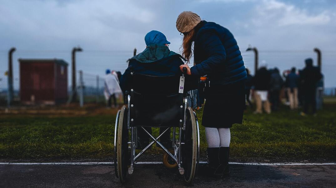 Άτομο σε αναπηρικό αμαξίδιο και μία γυναίκα στο πλευρό του