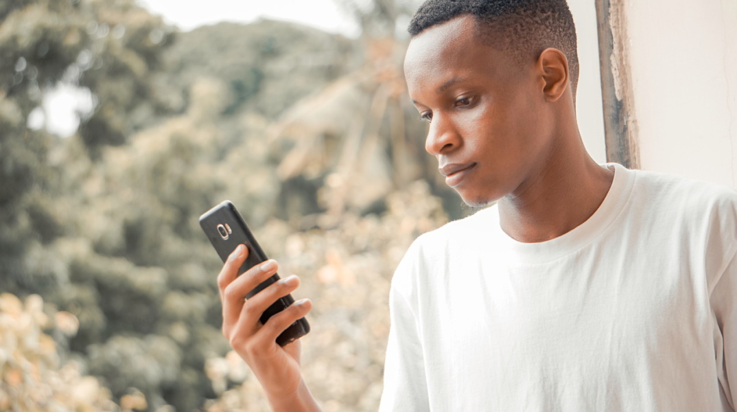 Μια φωτογραία ενός άνδρα να κρατάει ένα κινητό τηλέφωνο.