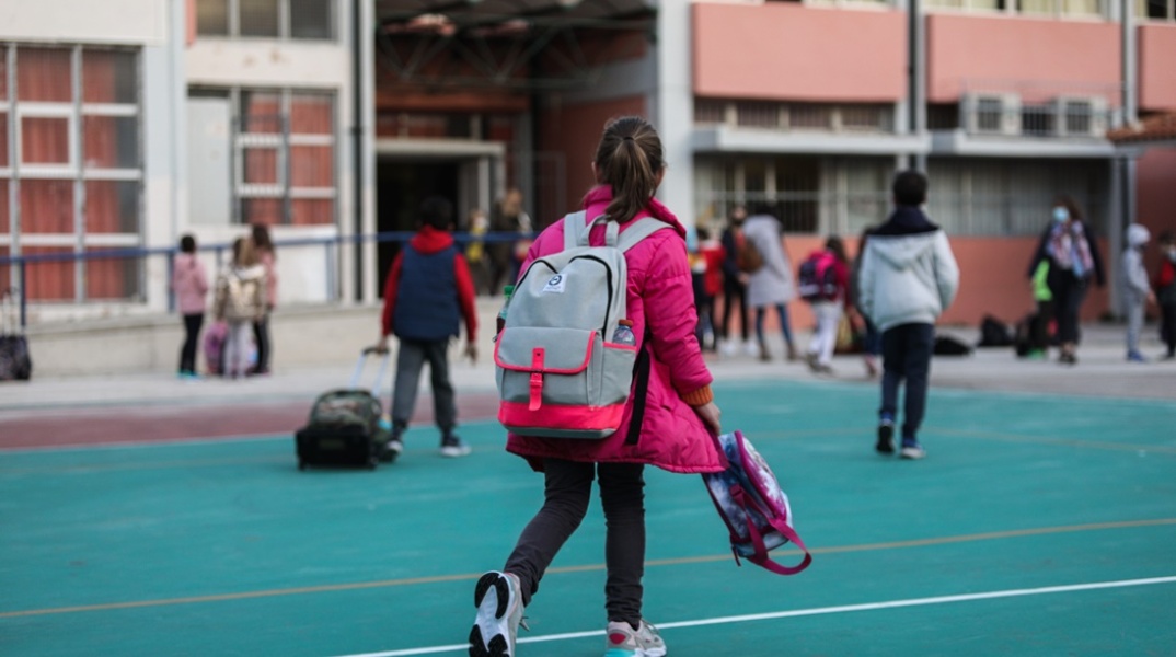 Σχολείο: Μικρή μαθήτρια φορά τη σχολική της τσάντα και κρατά την τσάντα με το φαγητό της