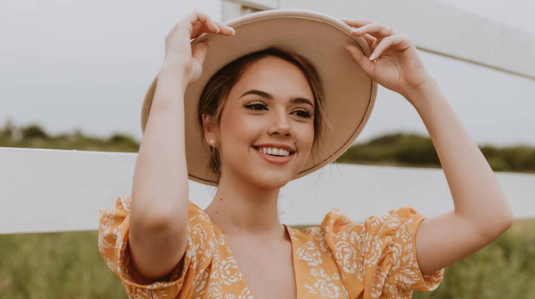 Νεαρή κοπέλα που φοράει καπέλο και χαμογελάει