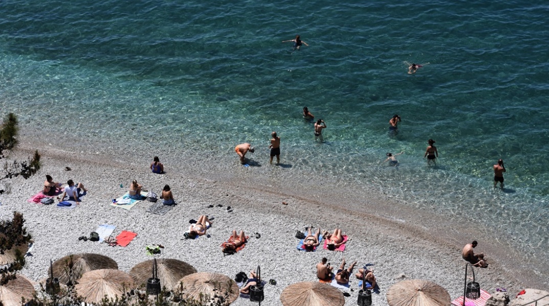 Λουόμενοι σε παραλία για να δροσιστούν από τις υψηλές θερμοκρασίες - Πολίτες απολαμβάνουν τη θάλασσα, όσο άλλοι κάνουν ηλιοθεραπεία