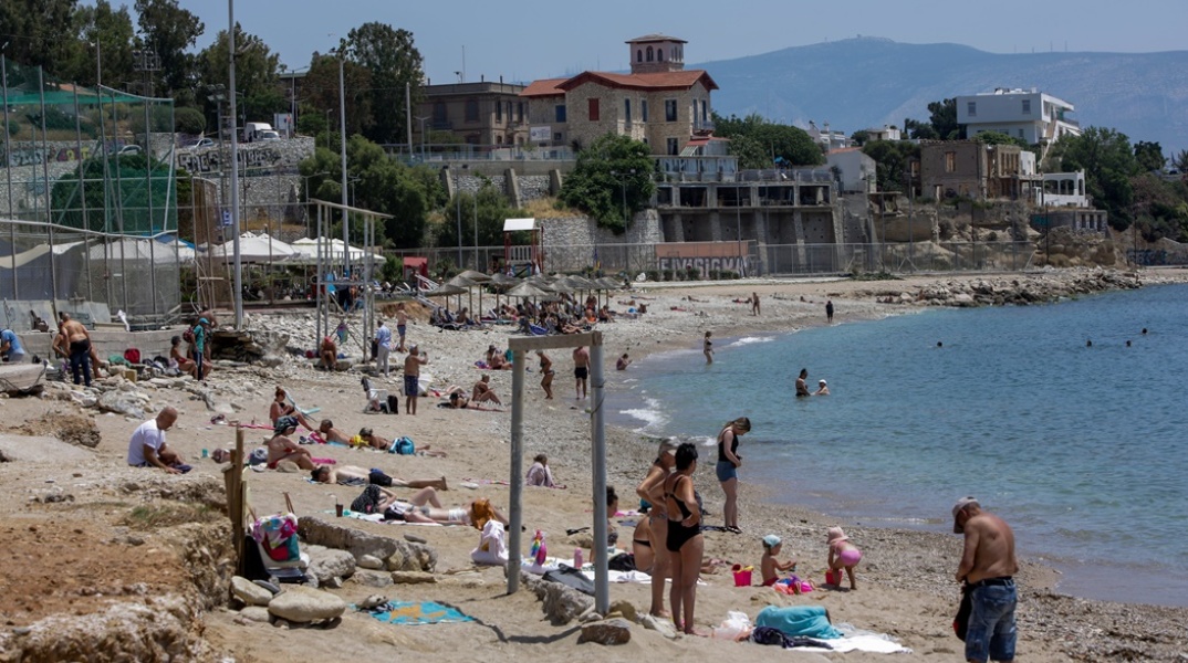 Λουόμενοι σε παραλία απολαμβάνουν την ηλιοθεραπεία τους - Ζέστη στην Αττική τον Μάιο του 2022