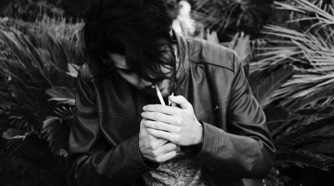 Ασπρόμαυρη φωτογραφία άντρα που καπνίζει