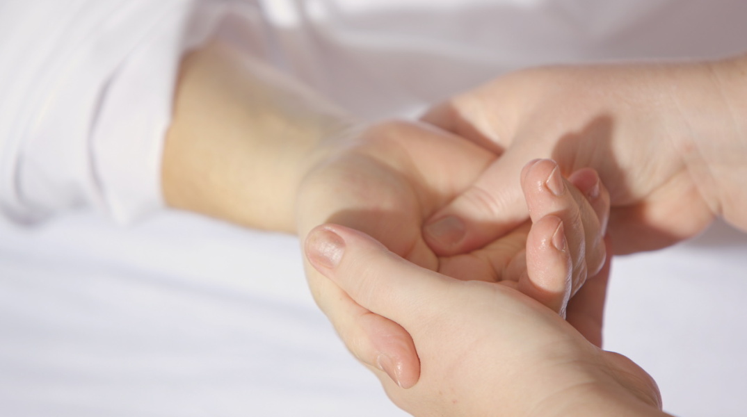 Εικόνα με μία γιατρό να εξετάζει ένα χέρι.