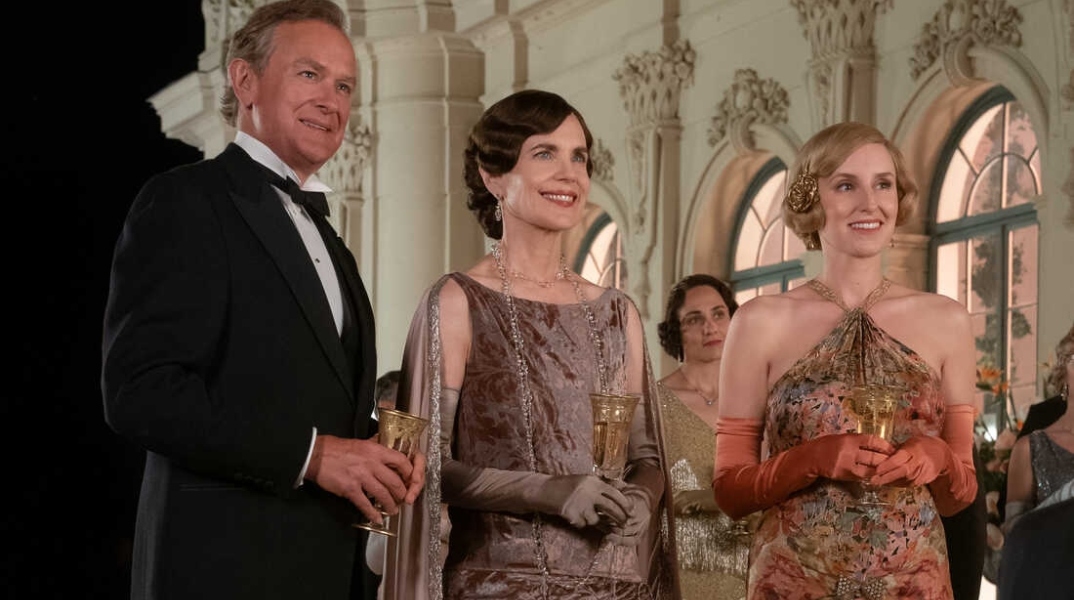 Downtown Abbey - Σκηνή από την ταινία όπου άνδρας και γυναίκες που κρατούν ποτά 