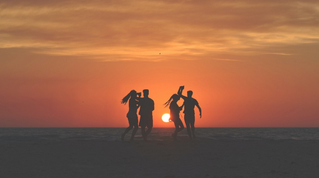 Τέσσερα άτομα χορεύουν στην παραλία. 