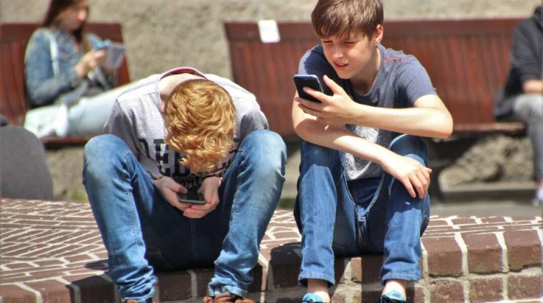 Δύο αγόρια που ασχολούνται με τα κινητά τους