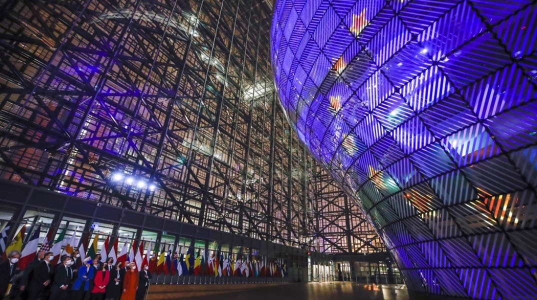 Eurogroup: Πολιτικοί κάτω από το σήμα της Ευρωπαϊκής Ένωσης που προβάλλεται σε κτήριο